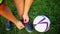 Professional football player at practice tying laces in the boots. Close-up with the ball.