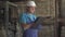 Professional foreman filling in documents standing in factory warehouse. Portrait of serious Caucasian factory worker in