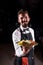 Professional garcon holds salad on a black background.