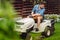 Professional gardener driving a riding lawn mower in a garden