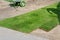 Professional gardener worker laying fresh artificially grown rolled lawn. Detail process of installation grass roll carpet at city