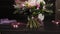Professional girl florist binds the bottom of the bouquet with silk pink ribbons. Dark studio. Slow motion