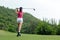 Professional golfer asian woman approach on tee off for swing and hitting golf ball and looking fairway in course.