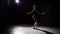 Professional graceful flexible ballerina dancing on her pointe ballet shoes in spotlight on black background in studio