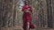 Professional graceful young woman in red dress dancing in the forest landscape. Dancer showing classic ballet poses and