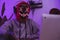 Professional hacker in a scary mask and red hood committing a crime. Internet and safety concept.