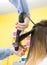 Professional hairdresser curling ombre hair with iron in beauty salon