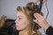 Professional hairdresser doing hairstyle for young pretty woman - making curls