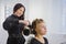 Professional hairdresser doing hairstyle for young pretty woman - making curls