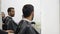 Professional hairdresser shows the back view of the haircut using mirror to handsome satisfied male client in a