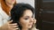 Professional hairdresser stylist makes hair styling with a hairspray for a beautiful young woman with long hair dyed