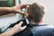 Professional hairdresser uses a hair clipper for fringing hair for a small boy