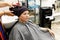 A professional hairdresser wipes his client`s head with a towel. Lady sitting with a towel on her head in a Barber shop