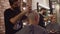 Professional hairstylist shaving head of client