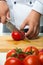Professional hands chopped tomatoes on a wooden board