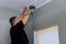 This professional handyman nailing wooden cornices over the curtains in a newly constructed home, over the window