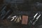 Professional hunters equipment for hunting. Rifle, knives, trophy sculps, ammunition, and others on a wooden black background. Tro