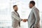 A professional Indian-Asian businessman shakes hands with an African American business partner