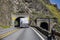 Professional industrial big rig semi truck with loaded flat bed semi trailer running on the winding road through a tunnel in the