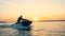 Professional jetskier is crossing open waters at the sunset