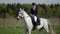 professional jockey is training on farm, riding white horse in field, sporty hobby