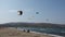 Professional Kite Surfers in action on Waves in sea.  Kites flying in air scenic background. People watching at the beach sitting