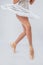 Professional legs of a young ballerina who puts on pointe shoes isolated on a white background in the studio. Ballet practice.