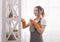 Professional Maid. Young Woman In Apron Cleaning Dust From Shelf