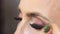 A professional makeup artist paints a thin black line on the eyelid of a girl with a brush