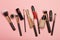 Professional makeup products with cosmetic beauty products, blushes, eye liner, eye lashes, brushes and tools on pink background