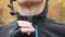 Professional male cyclist closing zipper on jacket and helmet clasp before outdoors workout on bike in autumn forest. Extra close