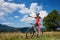 Professional male cyclist standing with bike on grassy valley, resting after cycling