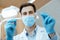 Professional male dentist in white coat, protective mask and gloves hold dental instruments and start job