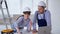 professional male and female builders in protective helmets and colors in their hands discuss design of new walls in