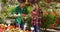 Professional male gardener standing in garden and showing plant to woman