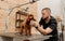 Professional male groomer making haircut of poodle teacup dog at grooming salon with professional equipment