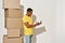 Professional male mover in casual wear making notes, holding clipboard, standing near a stack of cardboard boxes while