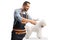 Professional male pet groomer holding scissors and grooming a bichon frise dog