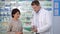Professional male pharmacist consulting female client in drugstore in slow motion. Intelligent Caucasian man with