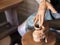 Professional male potter making ceramics on potter`s wheel in workshop, studio. Close up shot of potter`s hands