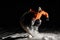 Professional male snowboarder in orange sportswear jumping on snow at night