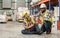 Professional male worker help his colleague after getting accident, injured leg while working in factory or warehouse. Safety,