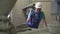 Professional man in safety helmet opening equipment on factory and using hammer. Portrait of Caucasian man in uniform