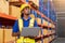 Professional Man Worker wearing hard hat checks stock and inventory with Clipboard in the retail of shelves with goods