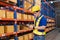 Professional Man Worker wearing hard hat checks stock and inventory with Clipboard in the retail of shelves with goods