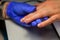 Professional manicure in salon, applying the base under the varnish. Hands of master in gloves and fingers of client, glare on