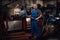 Professional mechanic stands next to the suspended flat engine and naked bike in garage