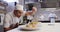 Professional mixed race male chef in a restaurant kitchen, putting food on a plate