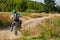 A professional motocross rider exhilaratingly riding a treacherous off-road forest trail on their motorcycle.