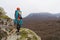 Professional mountaineer with a bay of rope stands on a high rock and looks into the distance